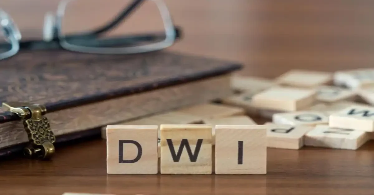 wooden letter tiles spelling dwi beside law book and glasses